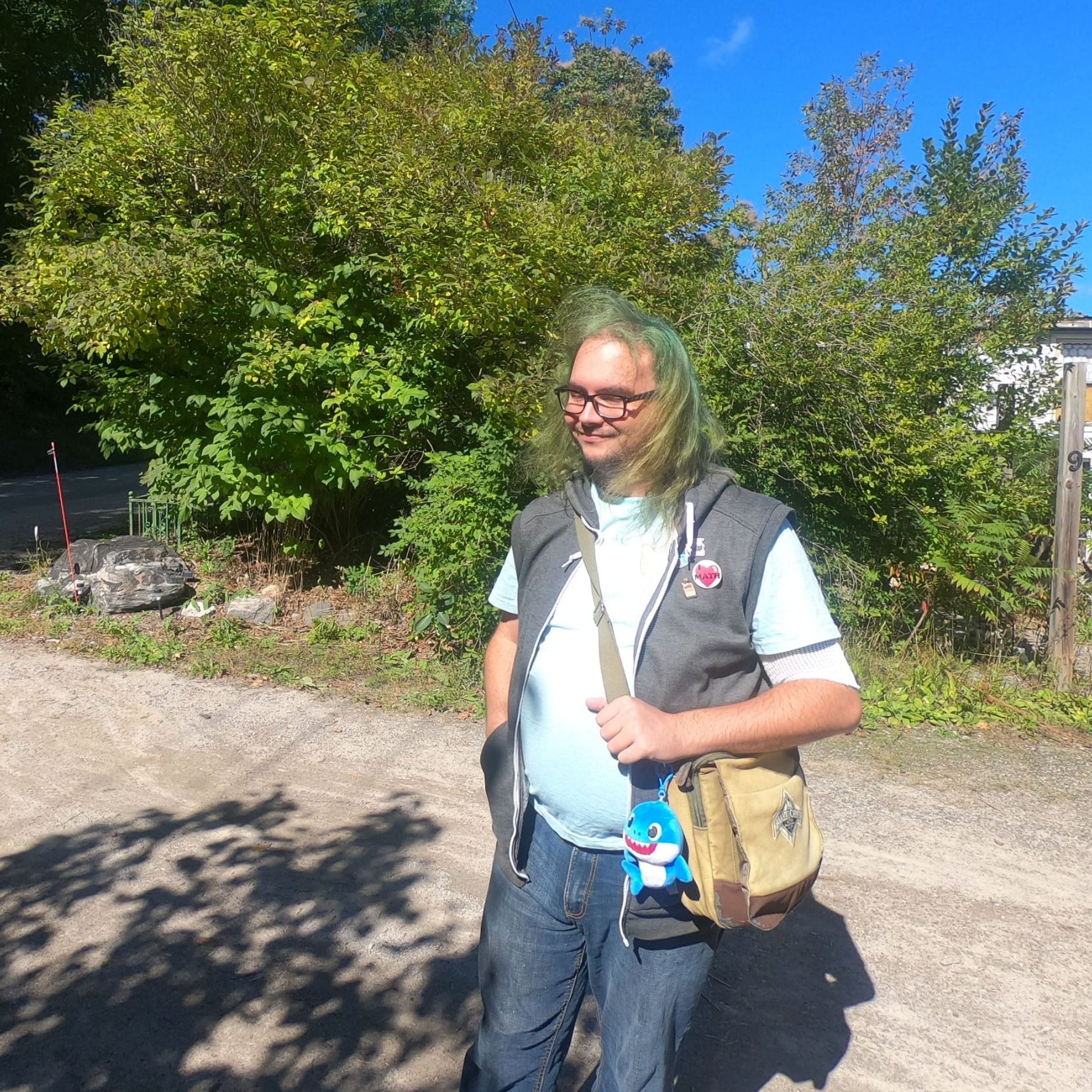 A man with long green hair stands in his driveway